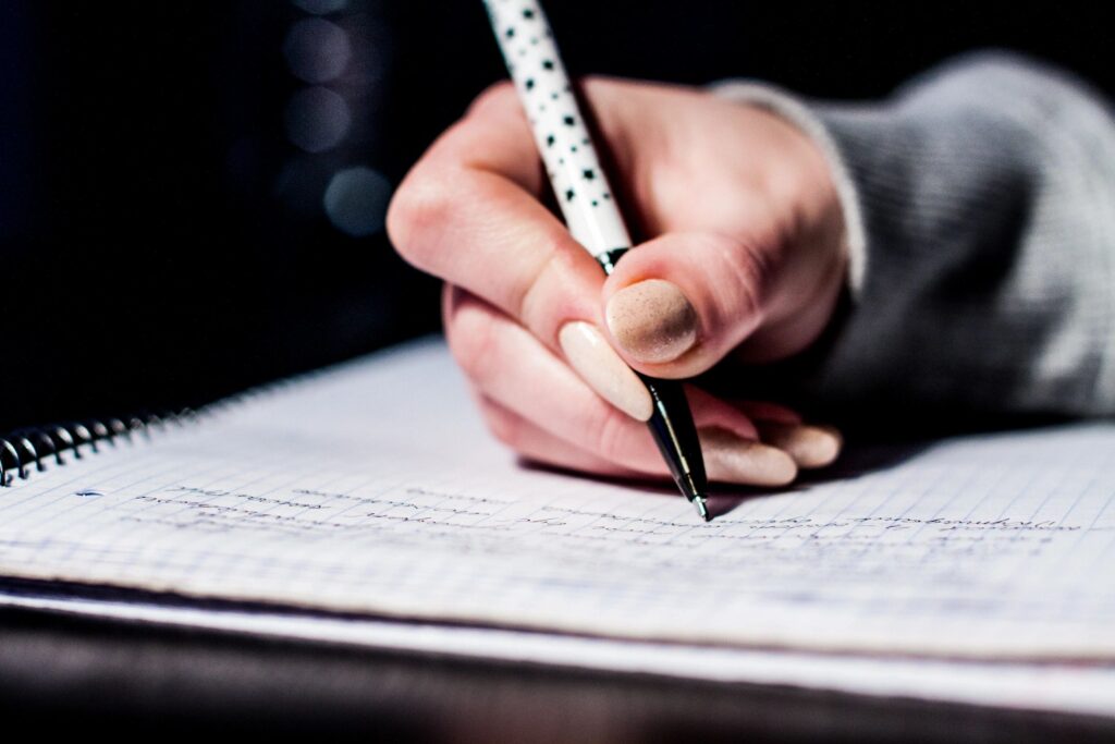 hand with a pen writing on paper