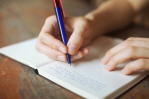 a hand with a pencil writing on a notebook