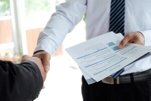 a guy shaking hands with another guy while holding a resume